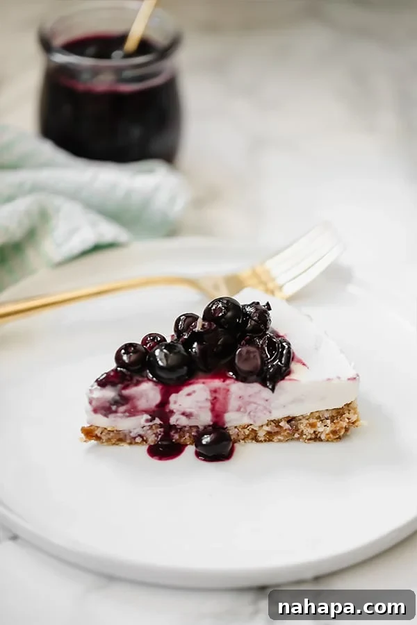 Creamy Dairy-Free Blueberry Lavender Cheesecake AIP Paleo 2 A slice of blueberry lavender cheesecake topped with blueberries on a white plate with a fork next to it.