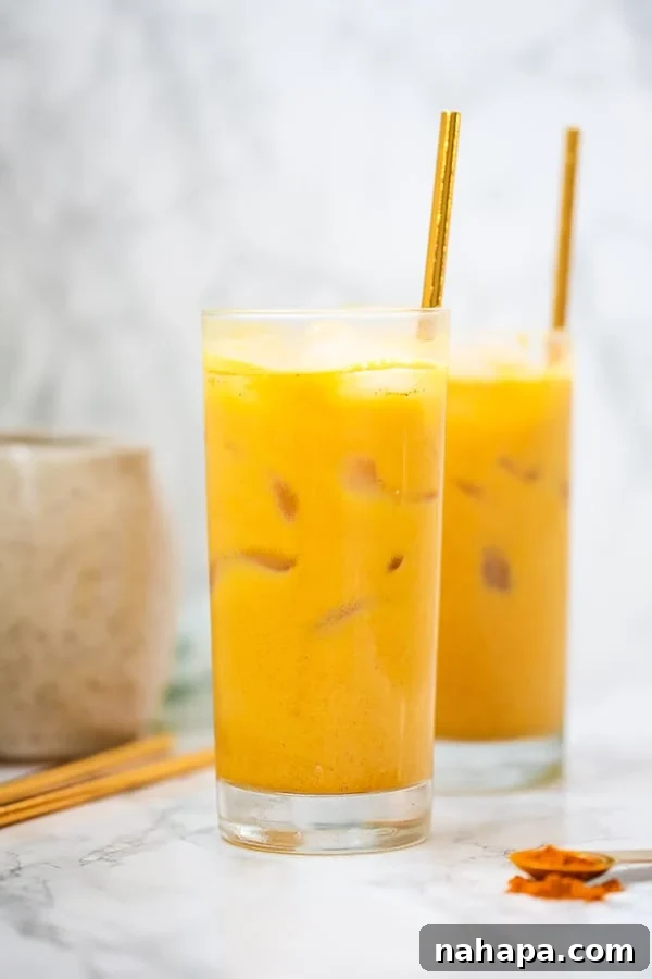 Two glasses filled with turmeric iced lattes and straws sticking in them.