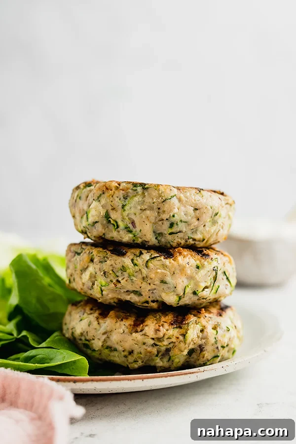 Greek chicken burgers stacked on a plate, showing the texture and even cooking
