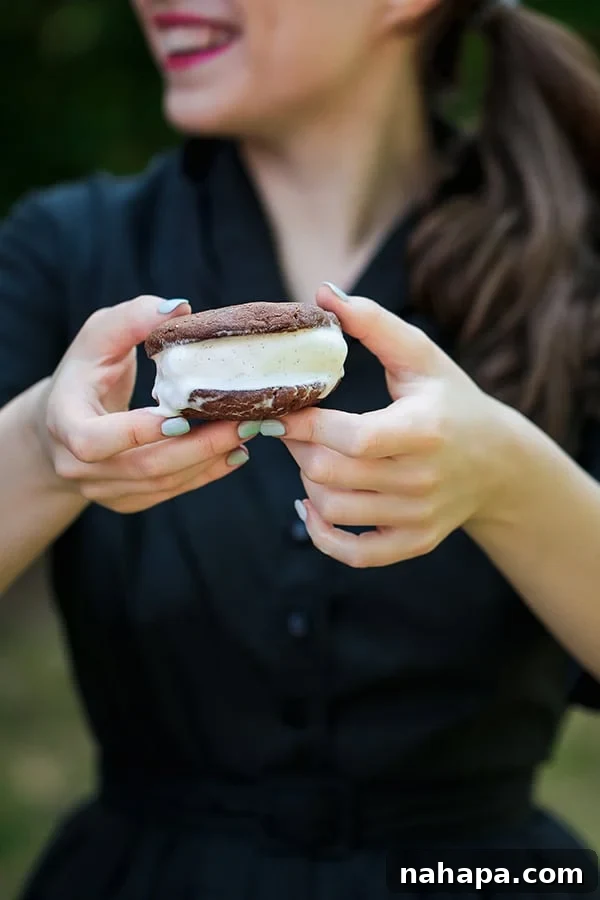 A person holding out a delicious homemade chocolate cookie ice cream sandwich, inviting a bite.