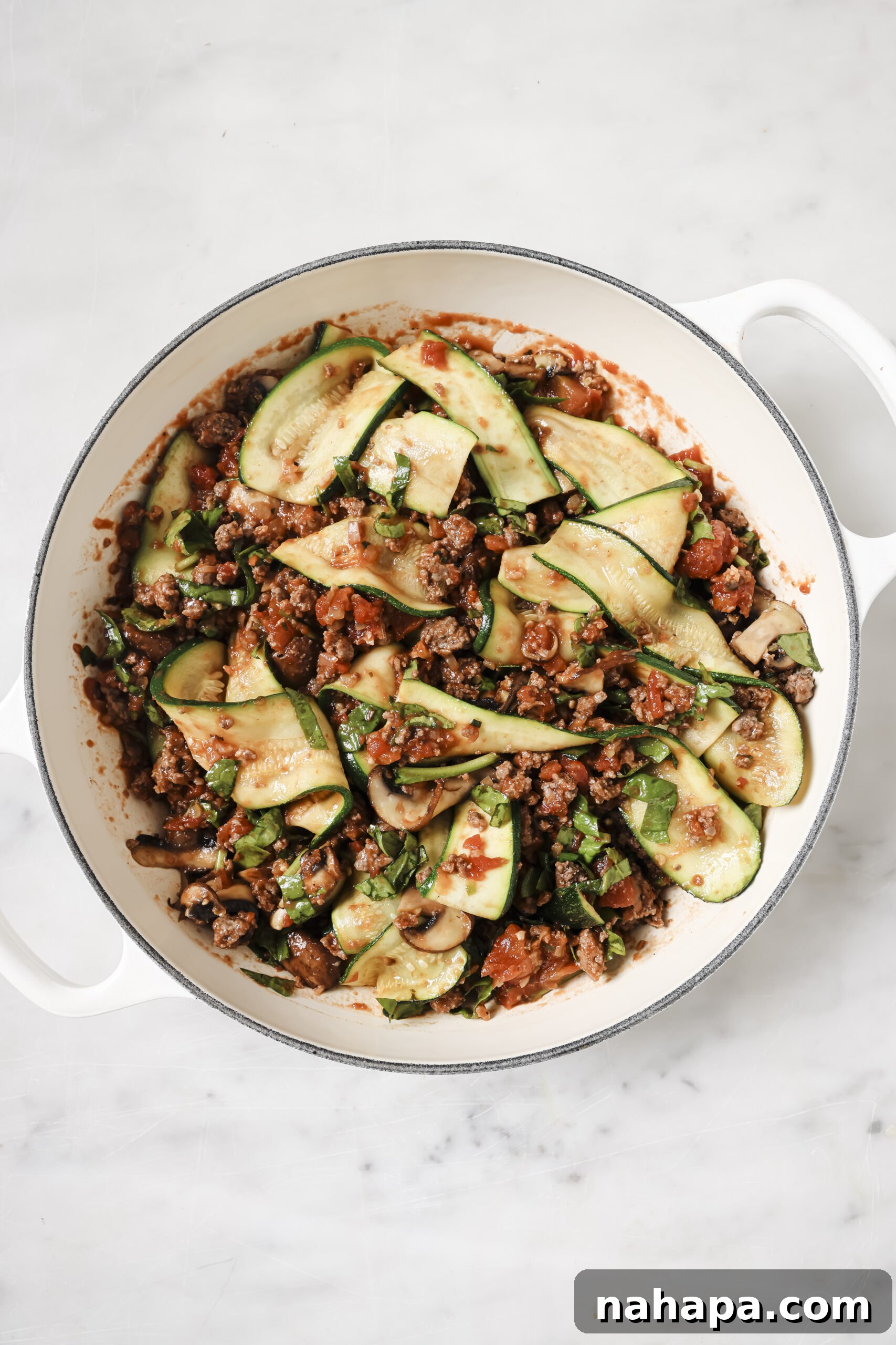 Close-up of the simmering lasagna skillet, with vibrant ingredients melding together in a rich sauce.