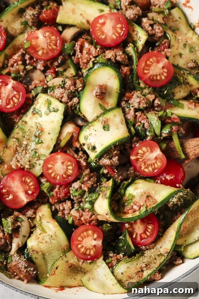 A wooden spoon rests in a pan of a delicious, bubbling lasagna skillet, ready to be served.
