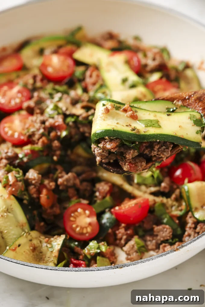 A serving spoon gracefully scoops a generous portion of the hearty one-pot lasagna skillet directly from the pan, highlighting its comforting texture and rich ingredients.