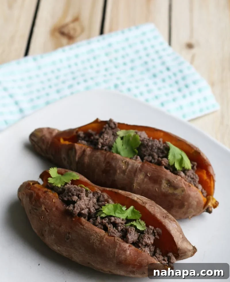 Hearty Bison Sweet Potato Boats 4 A perfectly cooked bison stuffed sweet potato sitting on a light wooden surface.