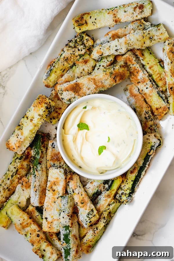A perfectly golden brown pile of baked low carb zucchini fries on a baking sheet, ready to be served, highlighting their crispy texture.