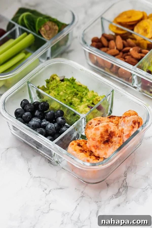 A glass meal prep container with chicken poppers, blueberries, and guacamole.