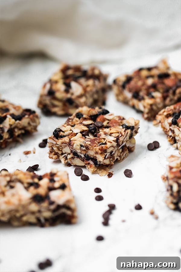 Several granola bar pieces spread on a counter with extra chocolate chips nearby, highlighting the delicious details