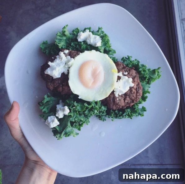 The Weekend Unfolds 6 Dinner plate with two grass-fed beef burgers, a baked egg, kale, and goat cheese.