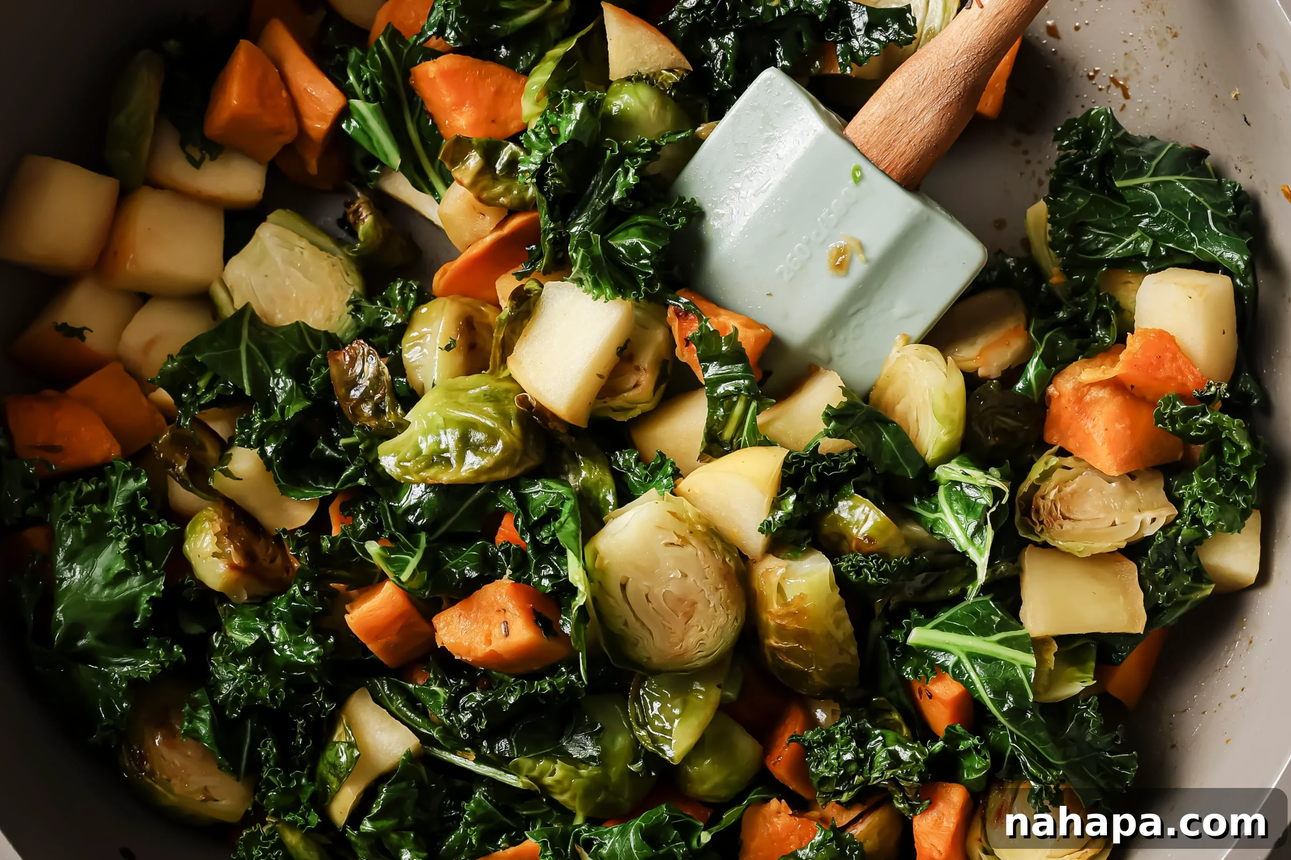 Diced pink lady apple and chopped kale being added to the pan with sautéed vegetables.