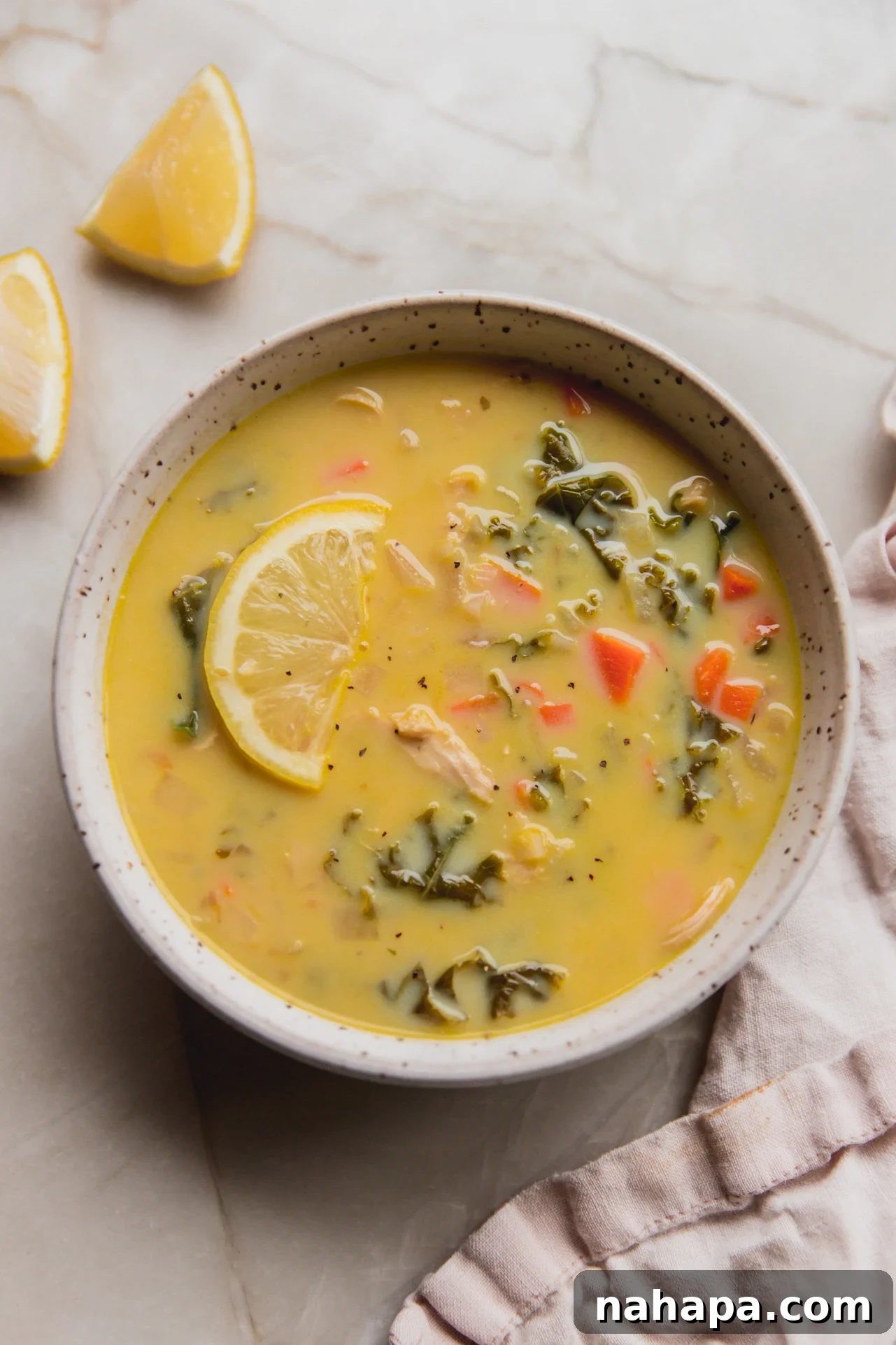 Velvety Greek Lemon Chicken Avgolemono 7 A beautifully presented bowl of Greek lemon chicken soup with a lemon slice, ready to serve.