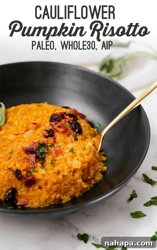 Creamy Paleo Whole30 AIP Cauliflower Pumpkin Risotto 5 A beautifully styled flat lay of creamy pumpkin risotto in a black bowl, garnished with fresh herbs and a wooden spoon, emphasizing its autumnal appeal.