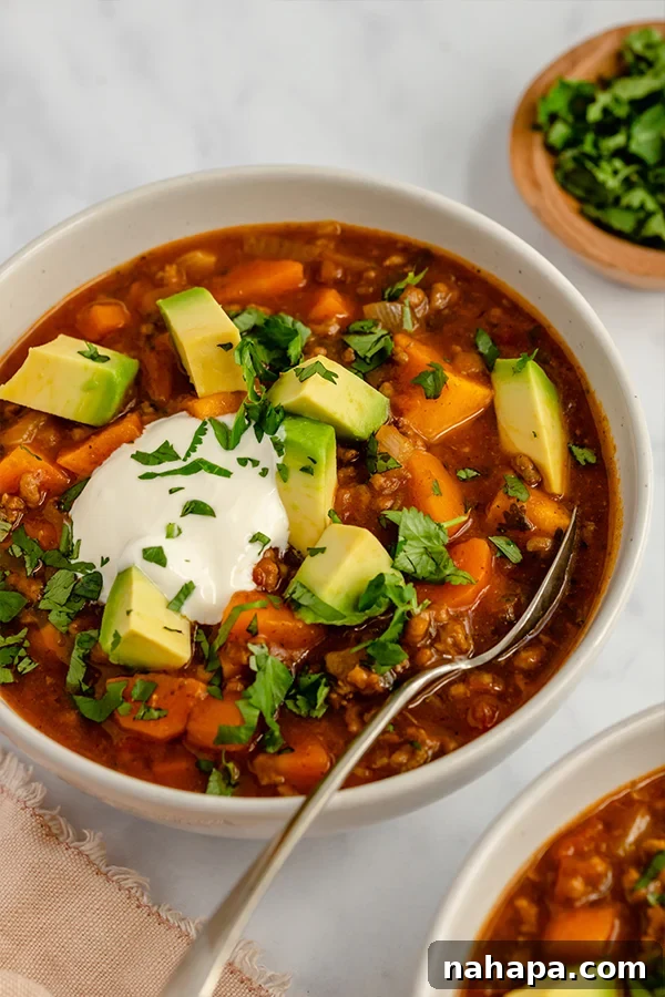 Paleo Pumpkin Chili served in a bowl with a spoon and fresh garnishes