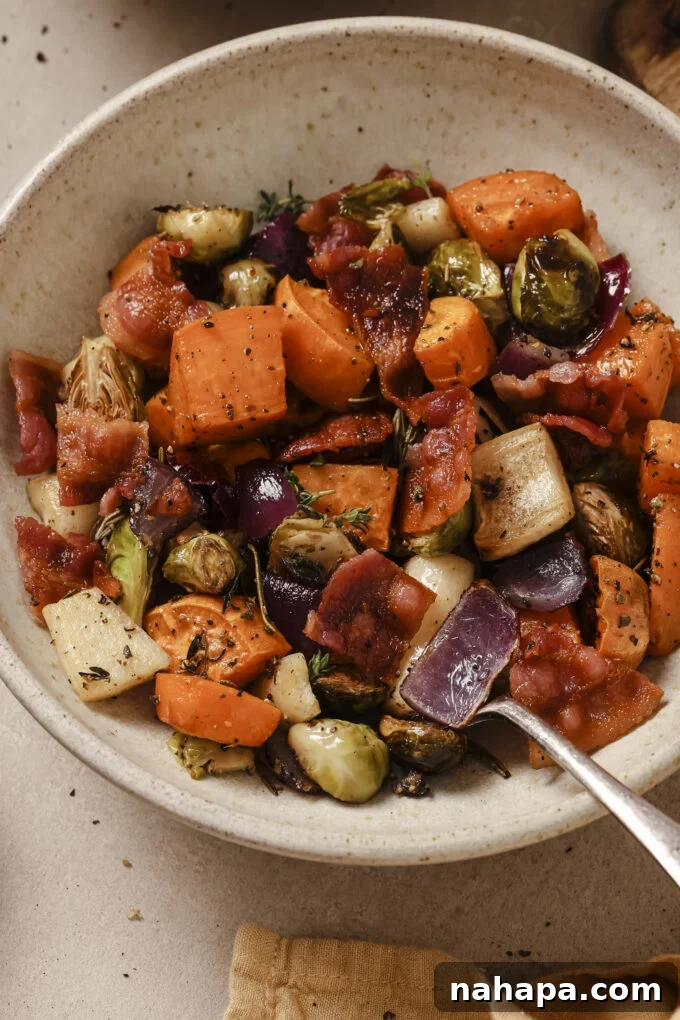 Bountiful Harvest Veggie Hash 8 A serving of roasted harvest vegetable hash with crispy bacon in a bowl, garnished with fresh herbs, showcasing its appealing texture and vibrant colors.