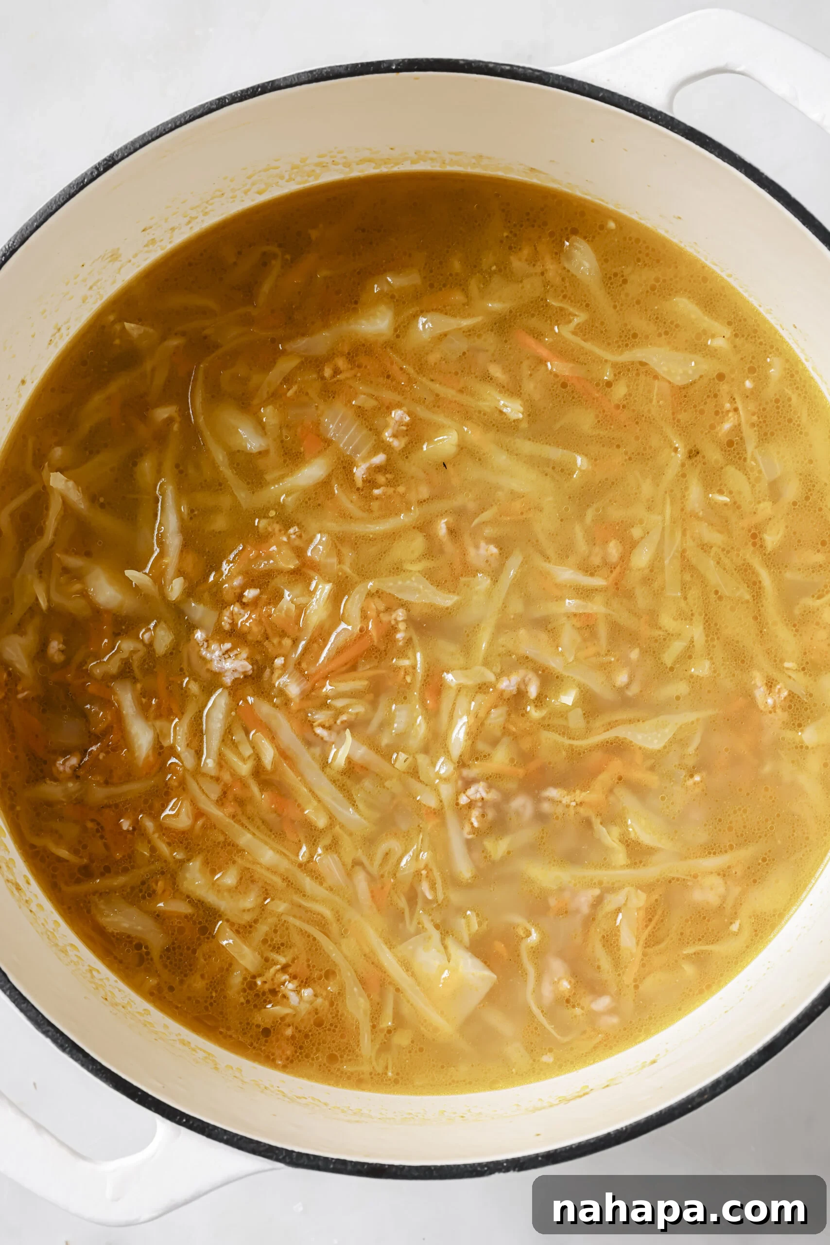 One-Pot Gluten-Free Egg Roll Soup 7 Finished egg roll soup simmering in a large cast iron pot, garnished with green onions.