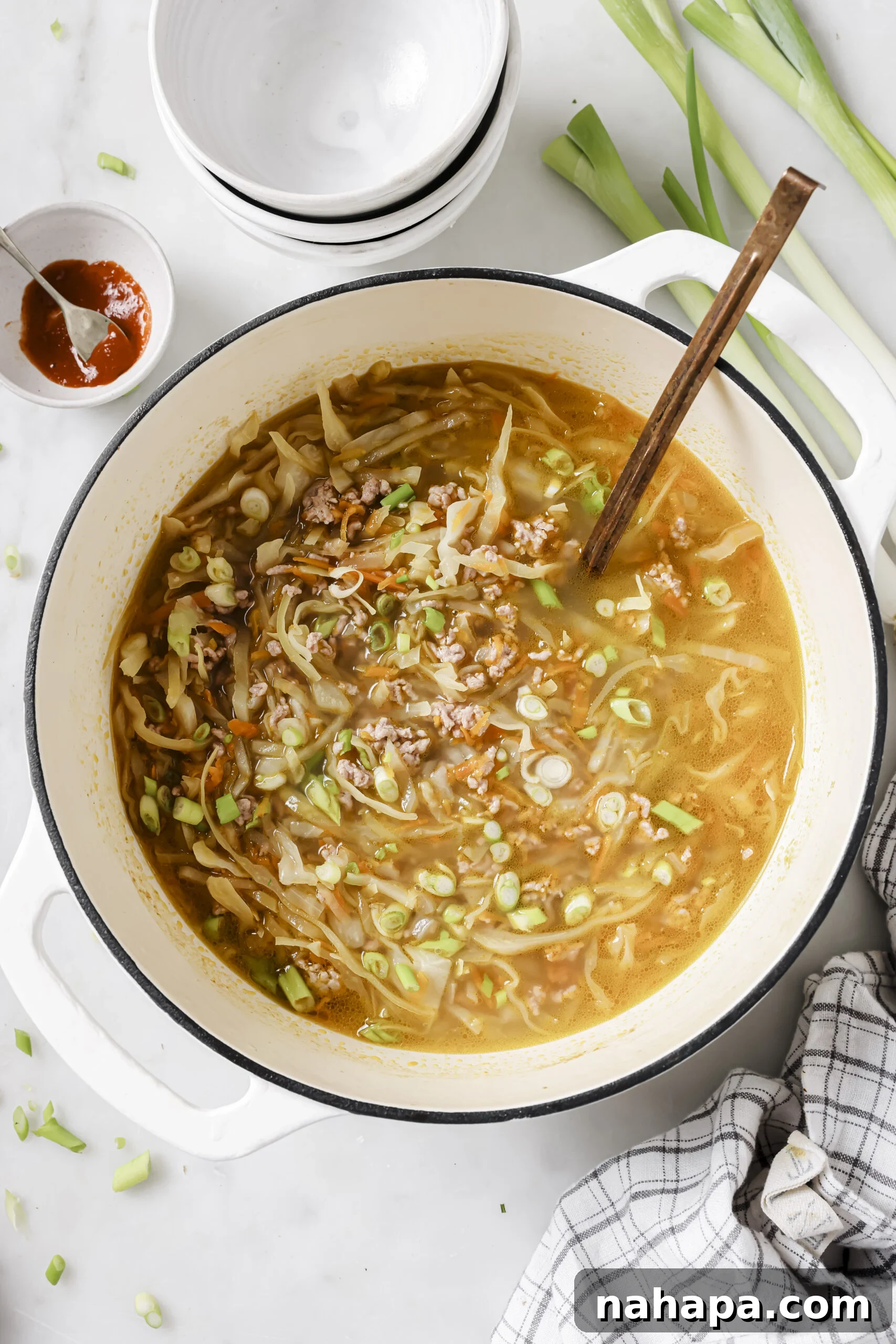 Egg roll soup in a large pot topped with green onions.
