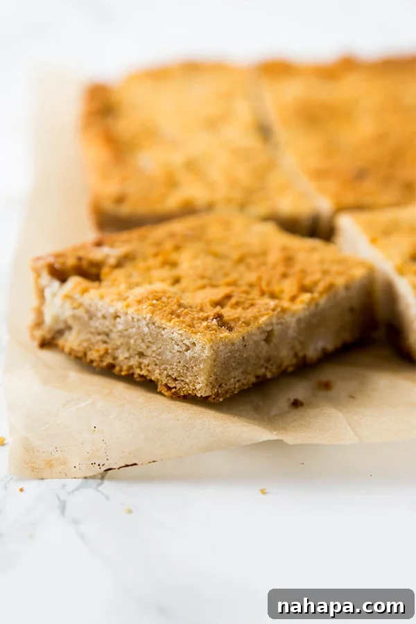 Two pieces of golden grain-free cornbread stacked on a white plate with fresh rosemary garnish.