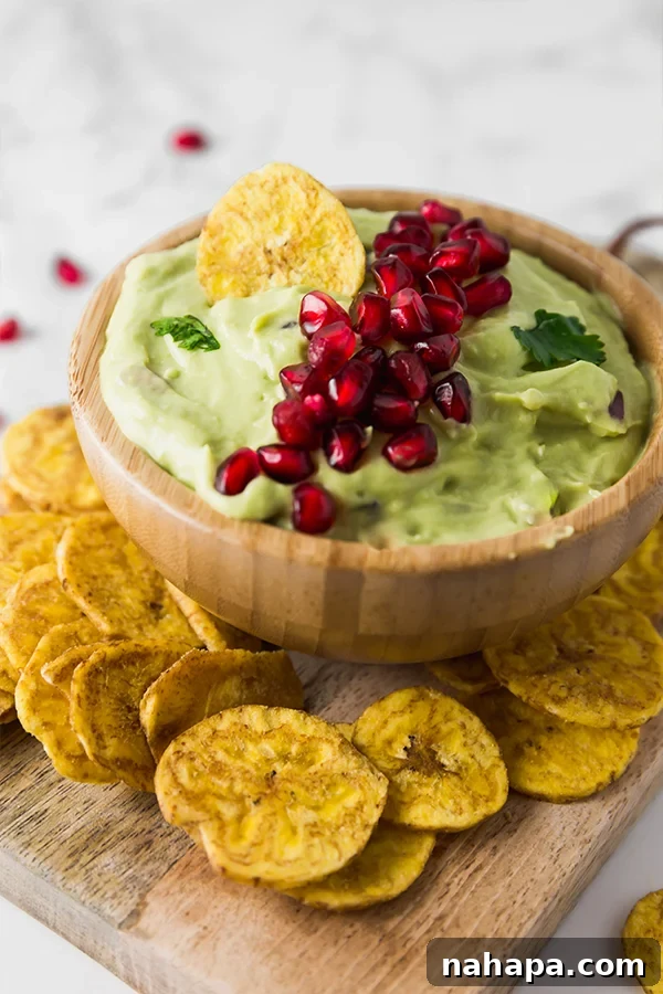 Tangy Pomegranate Guacamole Paleo AIP Vegan Approved 3 Close-up of vibrant green guacamole topped with bright red pomegranate arils and fresh cilantro, perfect for holiday gatherings.