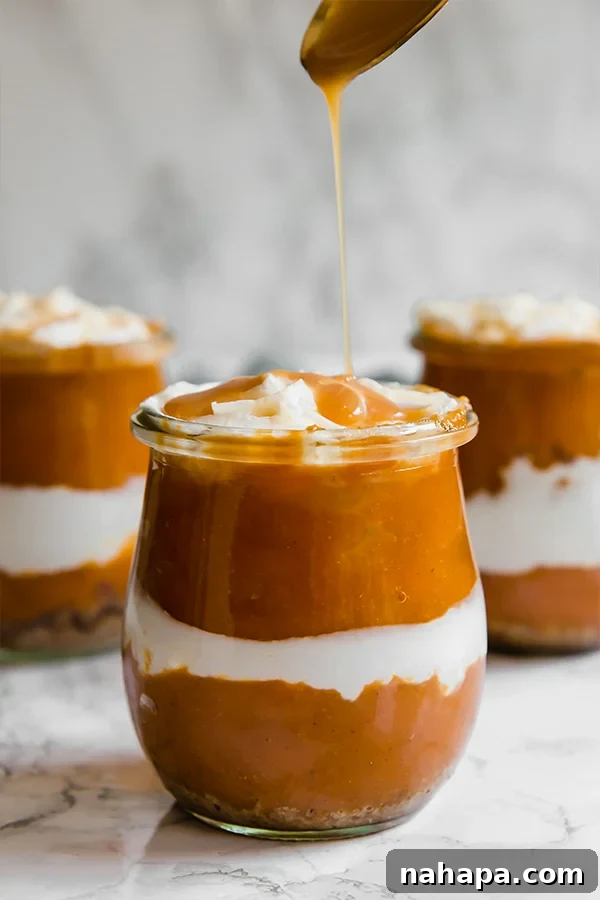 A layered pumpkin pie parfait in a glass, topped with whipped cream and a drizzle of caramel, showcasing its rich texture.