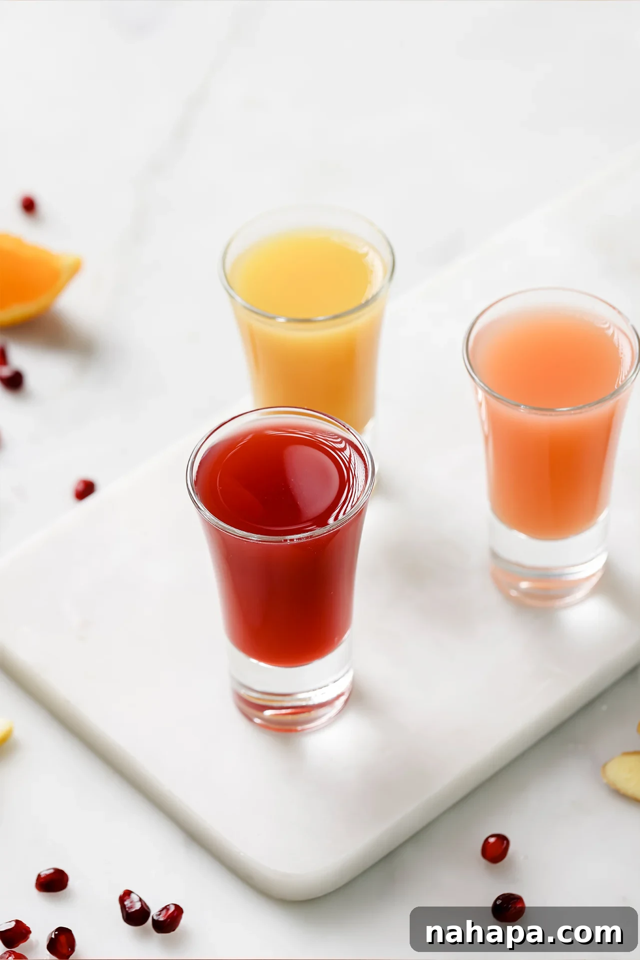 Three vibrant apple cider vinegar shots arranged on an elegant platter, ready to be enjoyed.