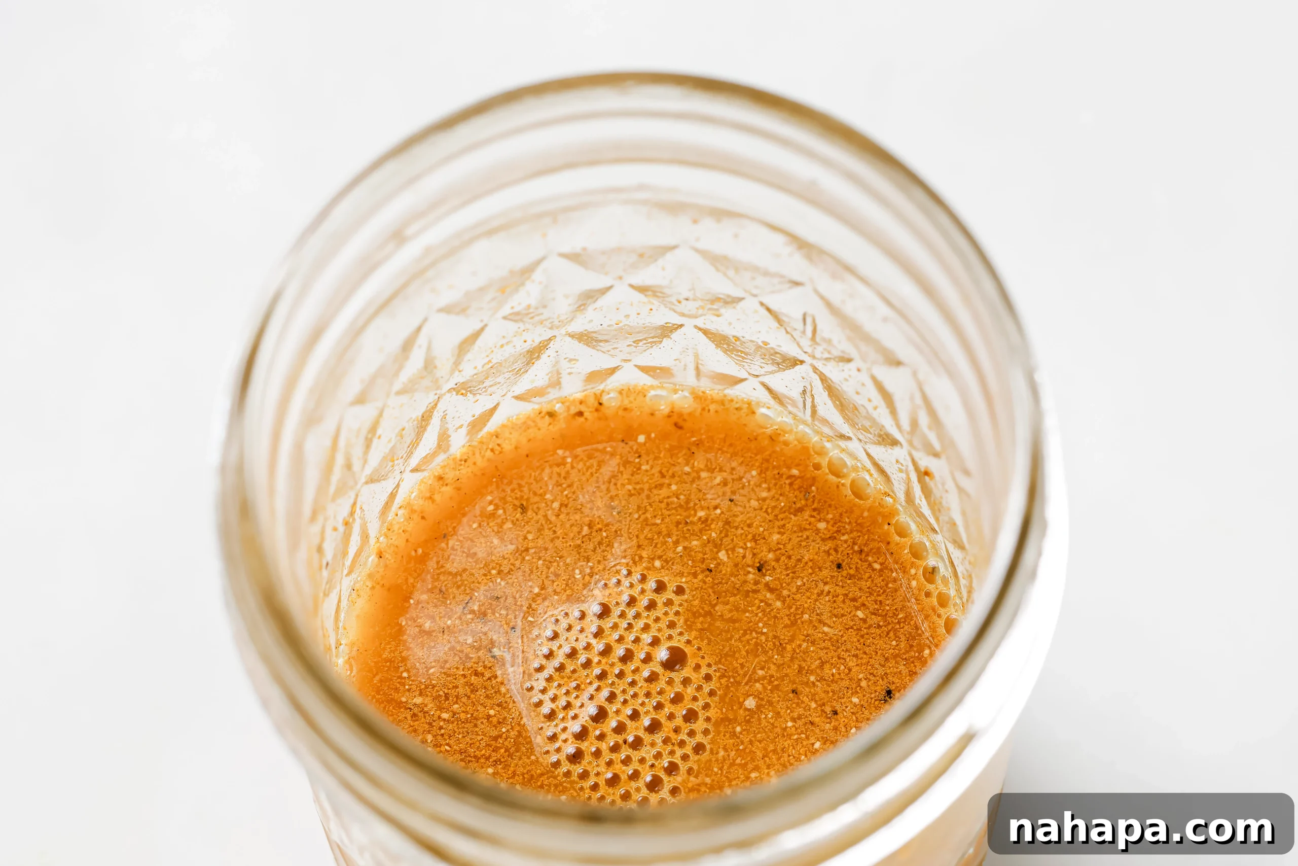 A small glass jar containing an apple cider vinegar shot mixture.