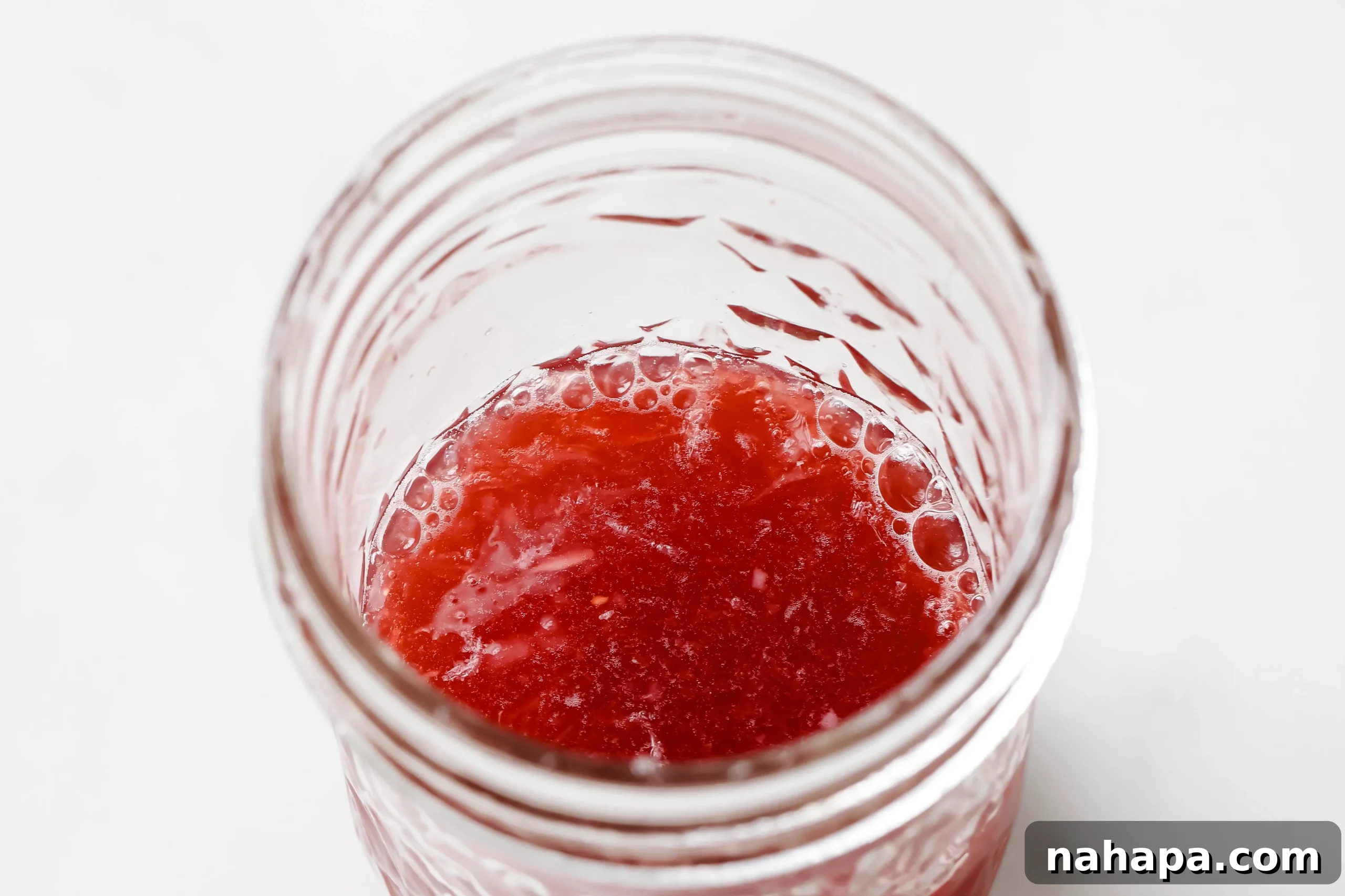 Two small glass jars, one filled with an apple cider vinegar shot mixture and another being filled.