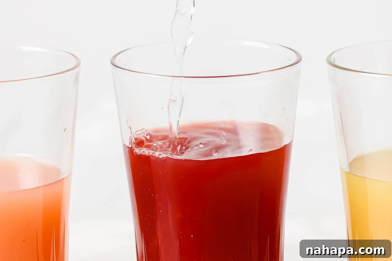 A glass containing an apple cider vinegar shot, with sparkling water being poured into it.