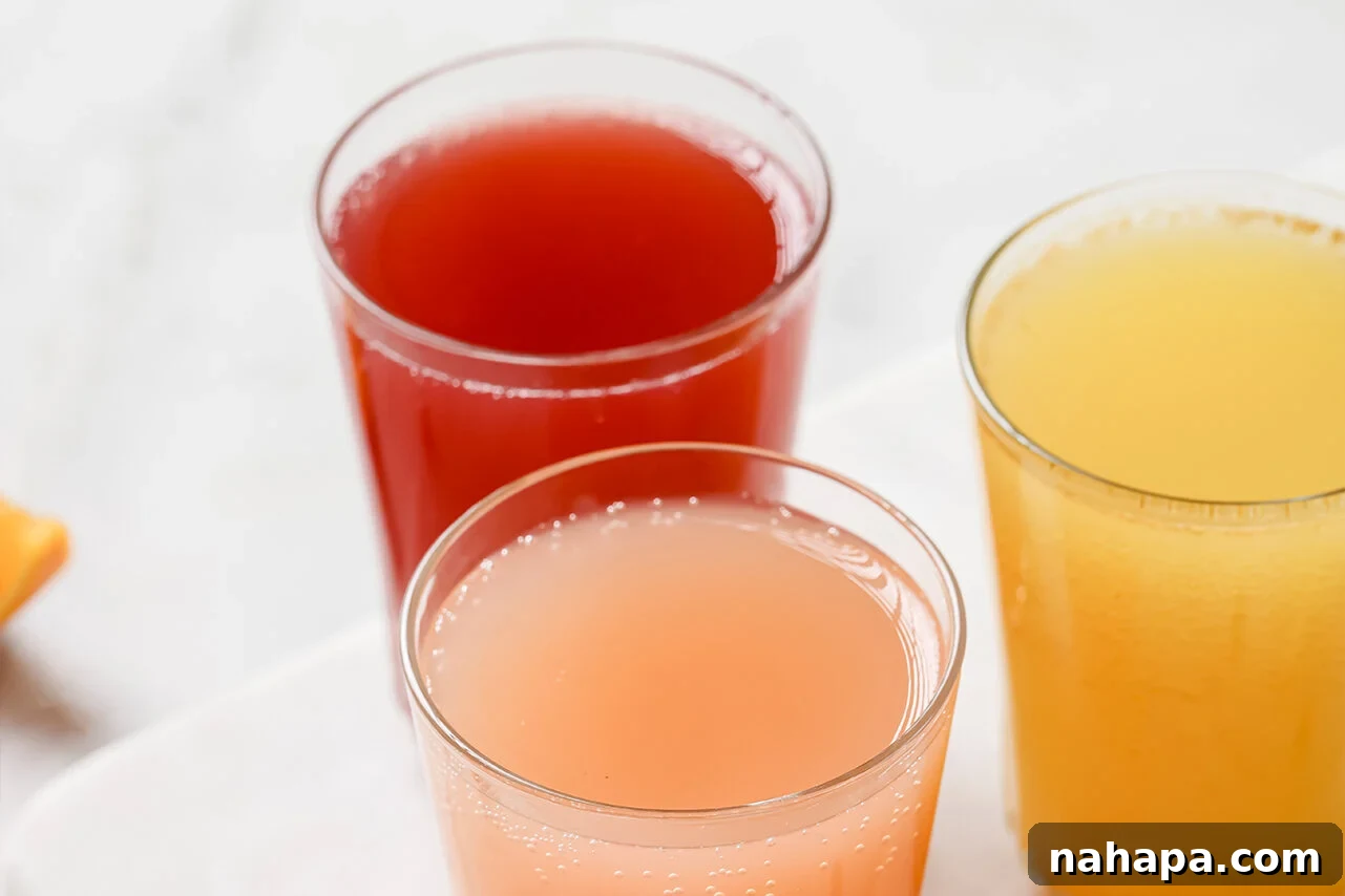Three glasses, each filled with a different flavor of diluted apple cider vinegar shot and ice.