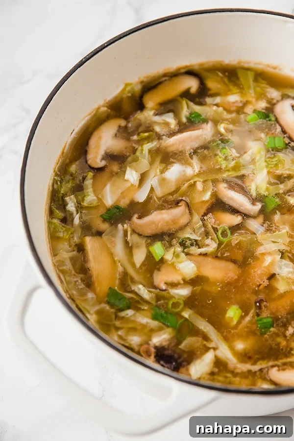 A gleaming white Dutch oven filled with a fresh, steaming batch of easy Paleo Hot & Sour Soup, perfectly ready to be served.