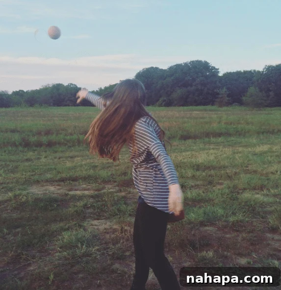 A person playfully throws a honeydew melon in a field, capturing a fun and lighthearted moment on the farm.