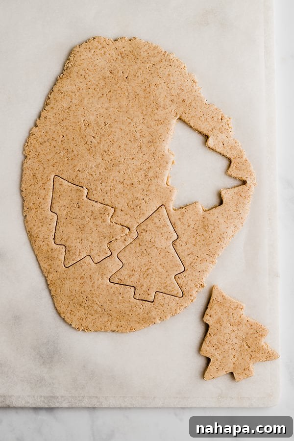 A tray of unbaked Christmas tree sugar cookies carefully arranged on parchment paper, ready for the oven.