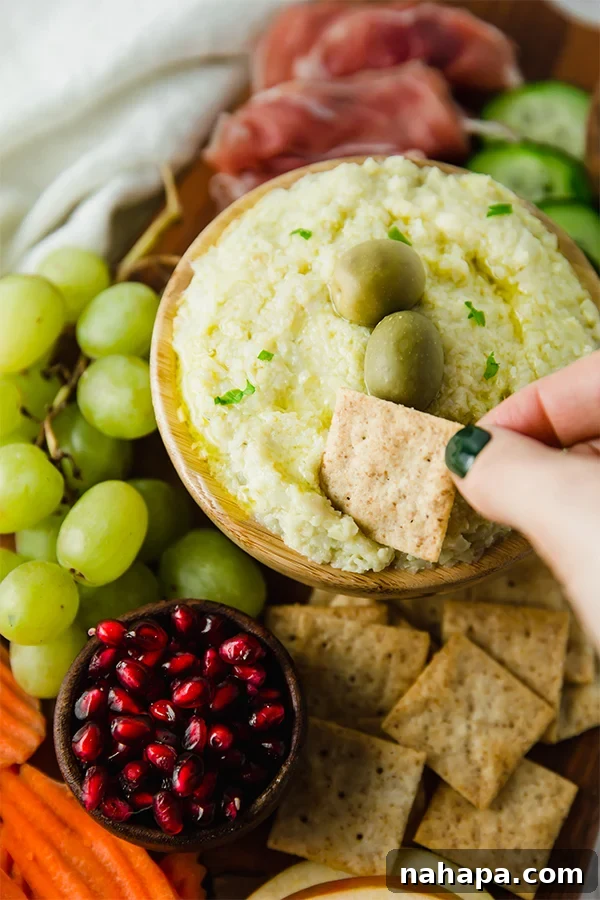 A vibrant and colorful paleo charcuterie board with a variety of meats, fruits, vegetables, and a dip.