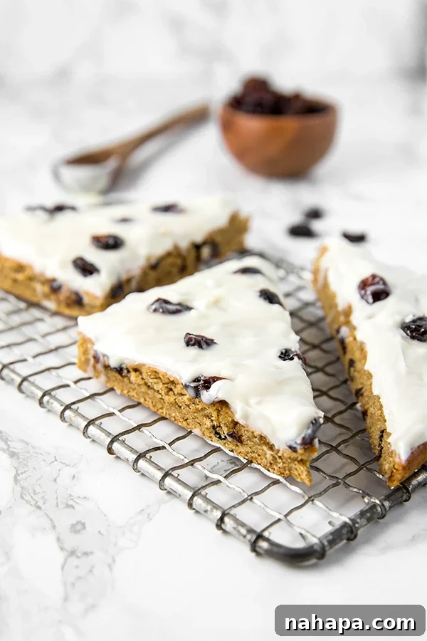 A close-up of a Paleo & AIP Cranberry Bliss Bar, showing the creamy frosting and dried cranberries.