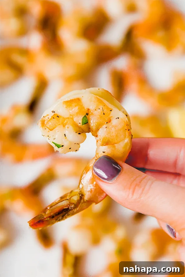 A hadn holding a baked shrimp with its tail on.