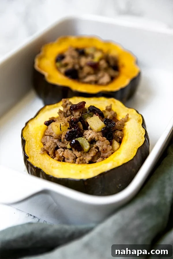 Paleo Whole30 AIP Stuffed Acorn Squash 3 Two halves of stuffed acorn squash served in a white ceramic dish, highlighting the colorful filling.