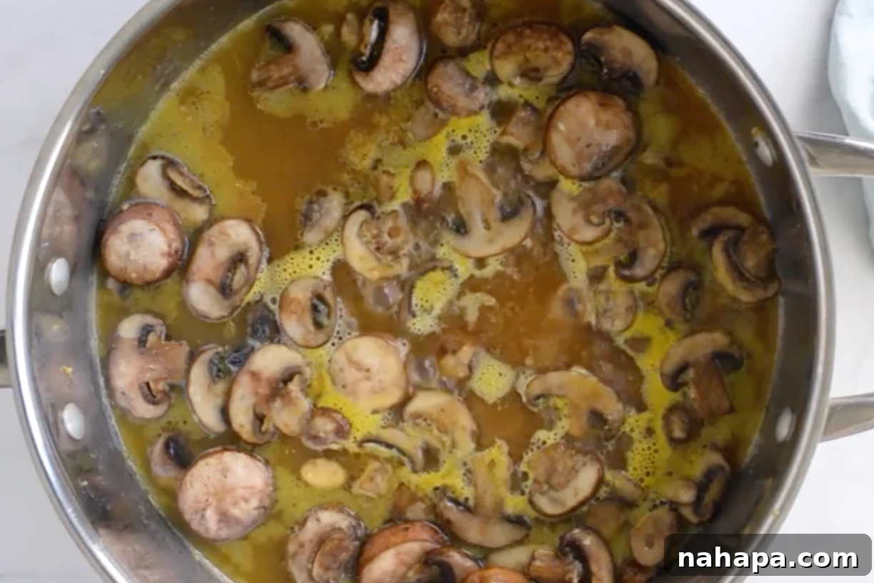 Sautéed garlic and mushrooms in a pan, with chicken broth and sherry vinegar being added to create the marsala sauce.