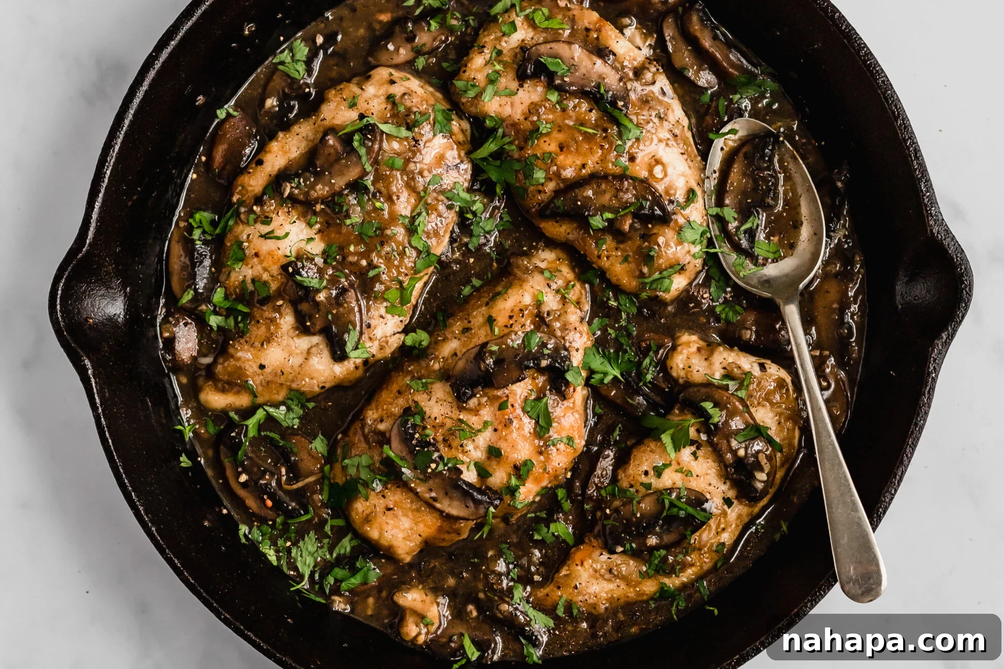 Cooked chicken cutlets returned to the simmering marsala sauce, garnished with fresh parsley.