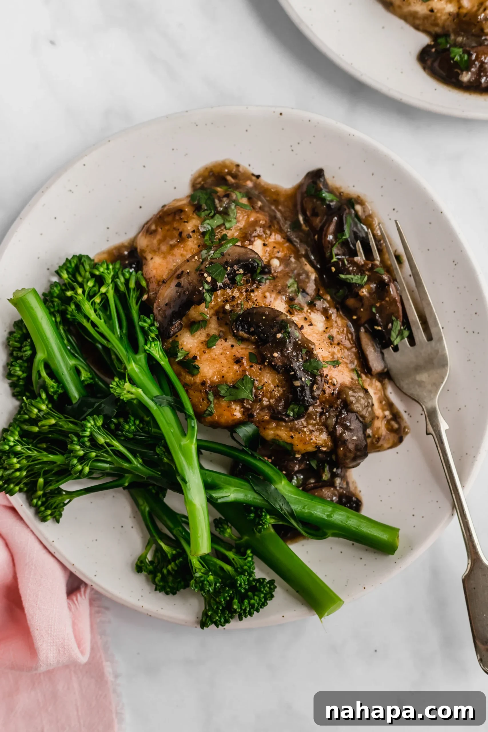 Gluten-free chicken marsala on a plate with fresh broccoli florets on the side.