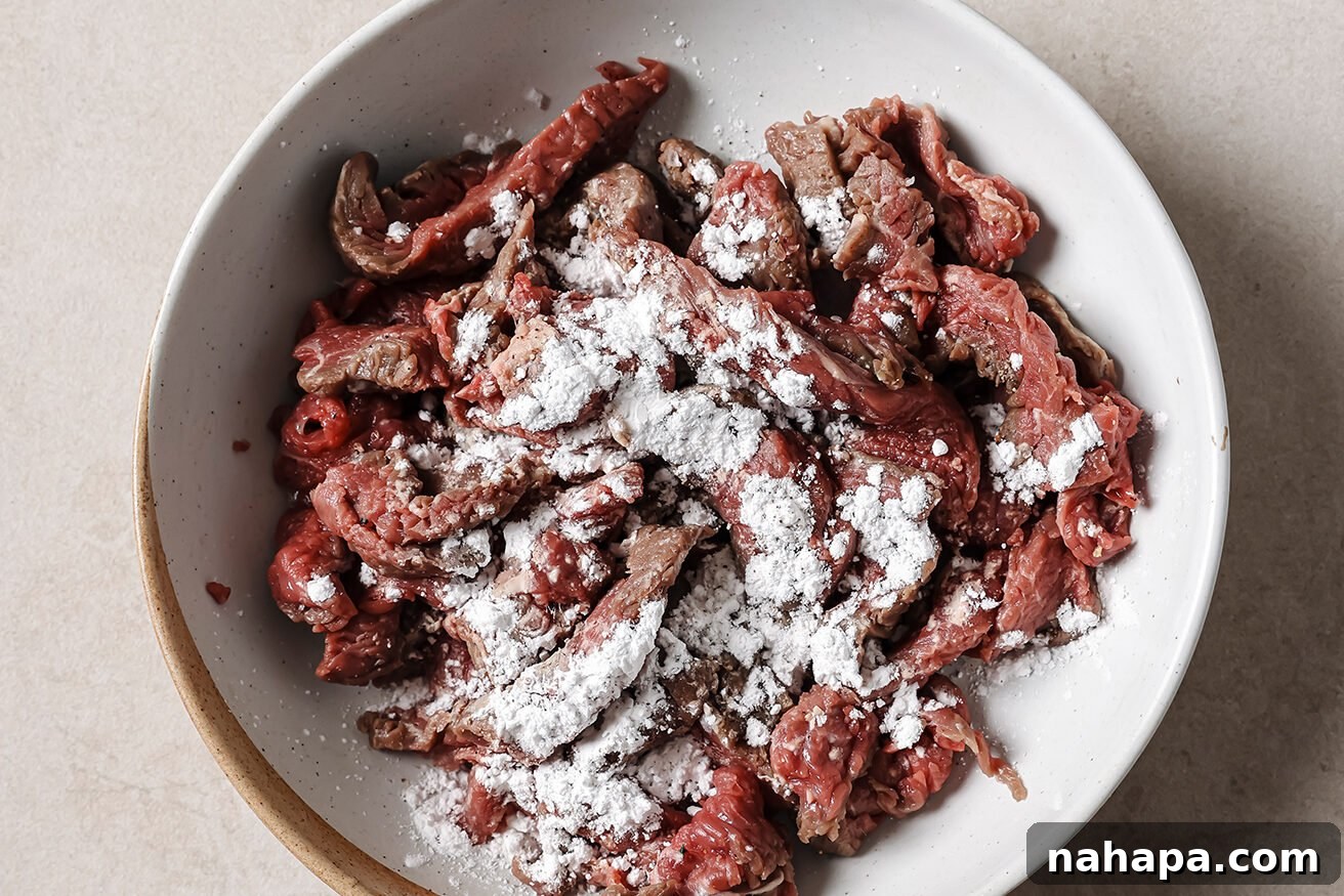 Sliced steak topped with arrowroot starch, ready to toss.