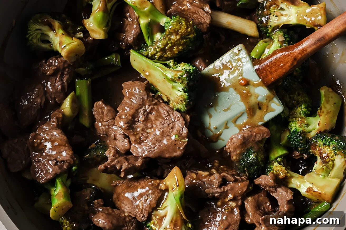 Cooked gluten free mongolian beef with sauce and broccoli in a pan.