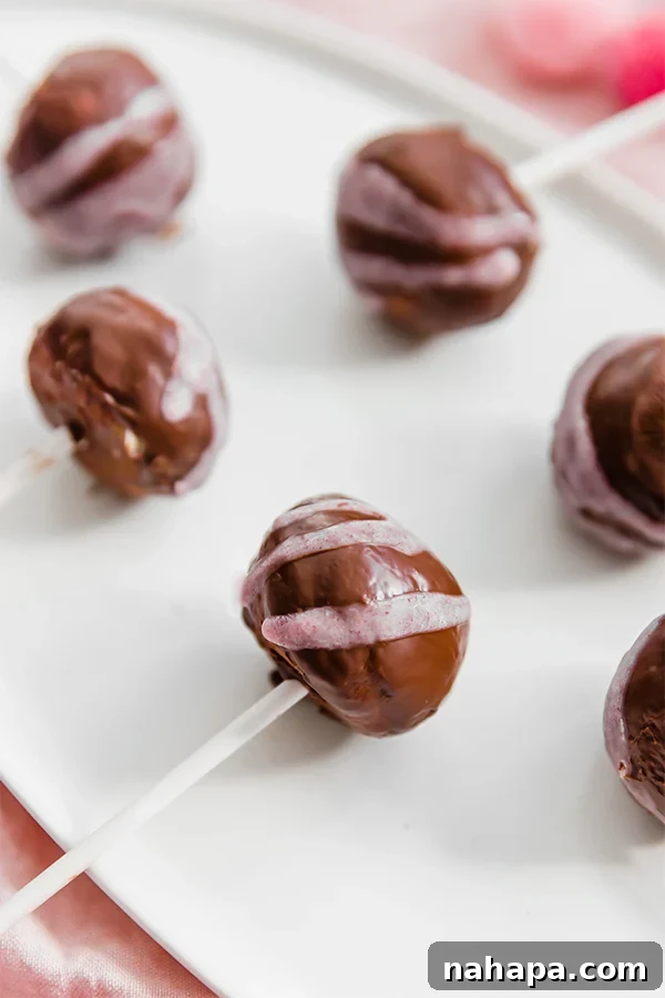 AIP and Gluten-Free No-Bake Paleo Cake Pops 3 Up close view of a pink drizzled no-bake cake pop, showcasing its smooth chocolate coating.