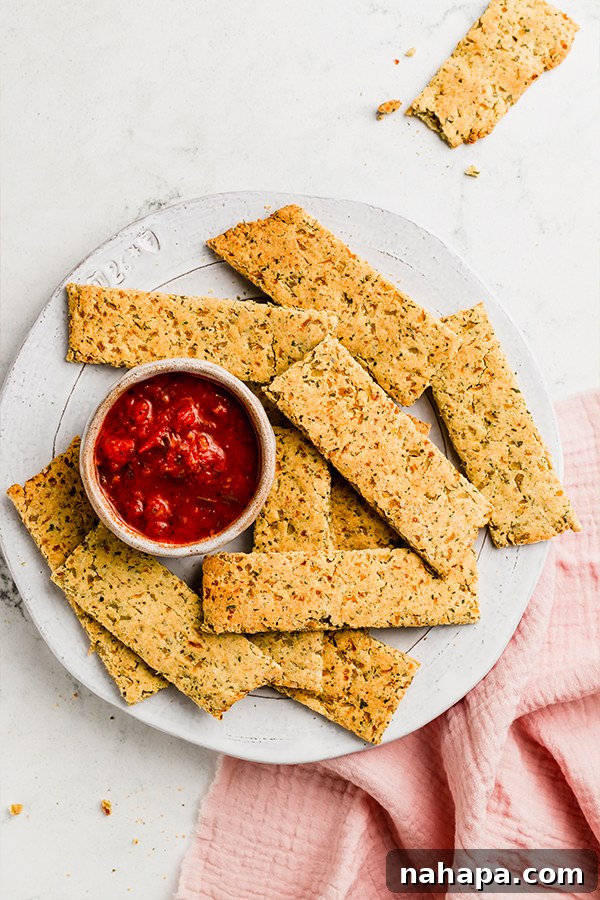 Grain-Free and Dairy-Free Cauliflower Breadsticks: Paleo and AIP Compliant 7 A close-up shot of cauliflower breadsticks arranged neatly on a plate with a small bowl of savory dipping sauce.