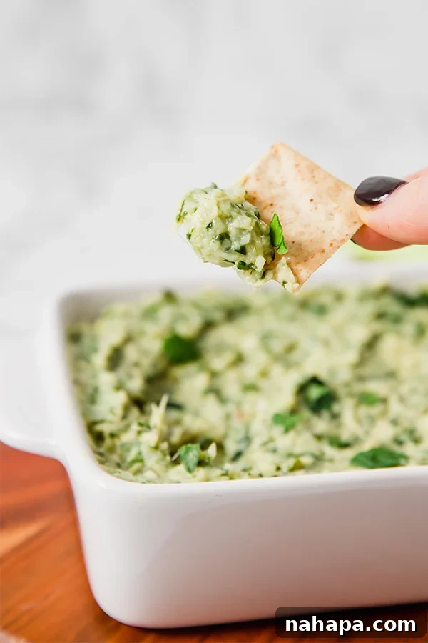 A close-up of a creamy paleo spinach and artichoke dip, served warm in a bowl, perfect for dipping vegetables or compliant crackers.