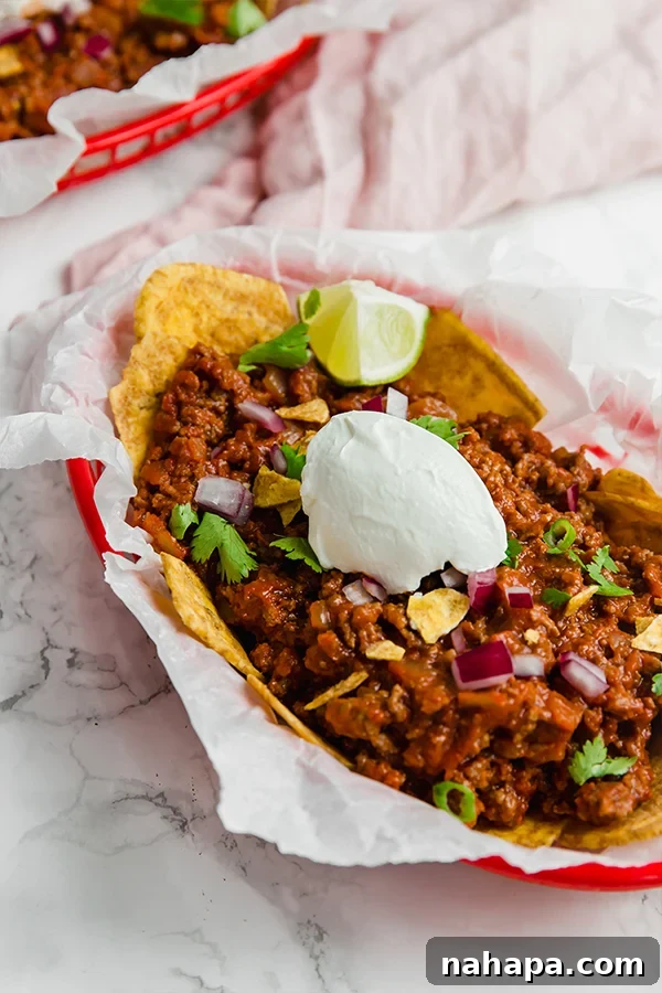 A hearty paleo Frito pie, featuring a savory ground meat base topped with crunchy plantain chips, mimicking the classic comfort food.