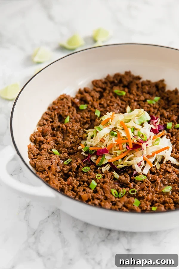 A white skillet filled with Asian sloppy joes and topped with coleslaw mix.