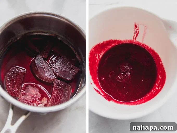 A close-up shot of a creamy pink beet latte in a clear glass mug, showing its layers and vibrant color, with a spoon resting in it.