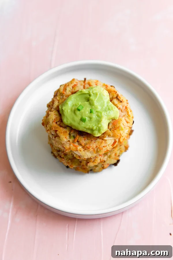 Two perfectly cooked Carrot Bacon Breakfast Fritters served with a side of creamy avocado mayo, highlighting their enticing appearance.