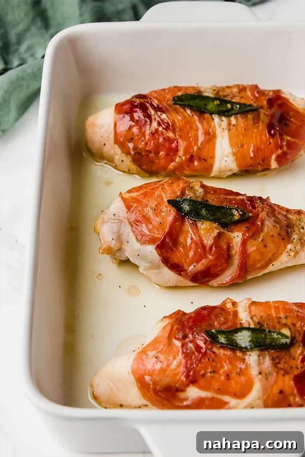 Close-up of baked prosciutto wrapped chicken with fresh sage and lemon