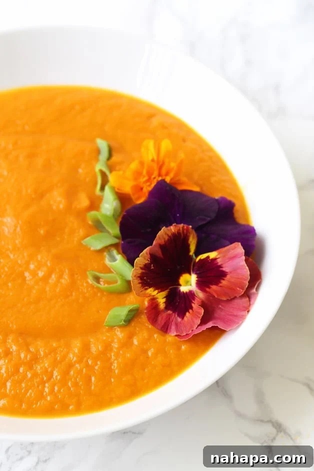 Vibrant Carrot Turmeric Spring Soup Garnished with Edible Flowers