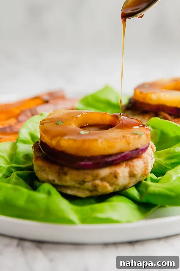 Paleo Whole30 AIP Tropical Teriyaki Chicken Burgers 5 Assembled Hawaiian Teriyaki Chicken Burger with grilled pineapple, red onion, and a generous drizzle of teriyaki sauce on a lettuce bun.