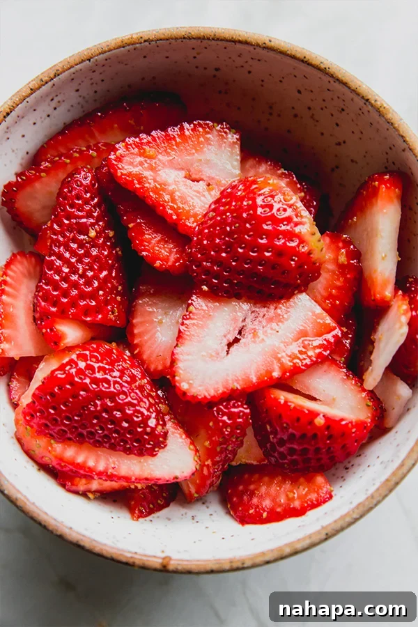 Strawberries being mixed with coconut sugar in a bowl, prepared for maceration.